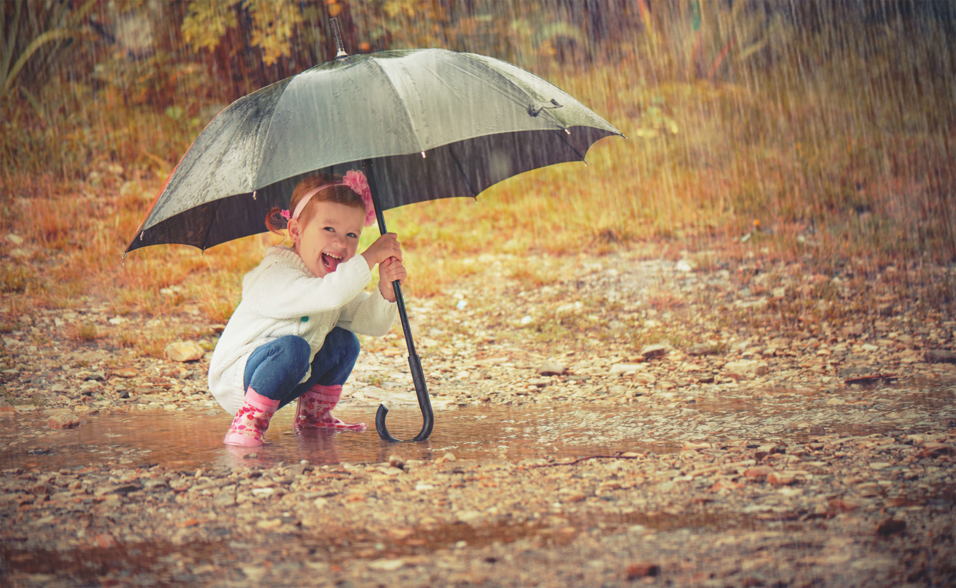 Little girl holding umbrella in the rain
